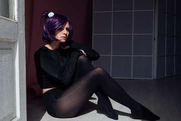Beautiful woman anime cosplayer with purple hair in black fashion clothes