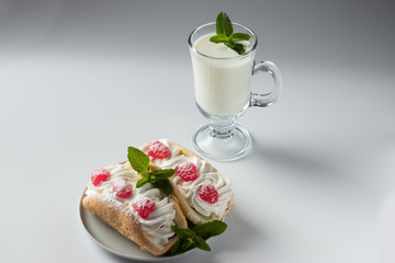 Kefir is decorated with a leaf of mint, a fermented drink. Air cake on a saucer on a white background