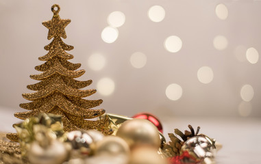 Gold Christmas toy tree, balls and mini gifts on the background of gold bokeh lights