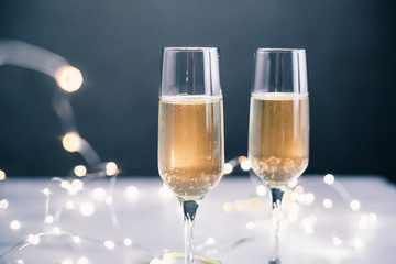 Champagne glasses on the table with a glowing garland