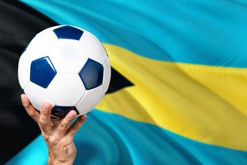 Naklejka premium Bahamas soccer concept. National team player hand holding soccer ball with country flag background. Copy space for text.