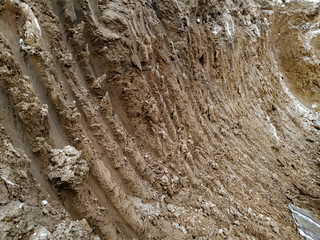 Lines made in mud of bulldozer excavator of working among the dirty ground of excavation site industry while digging on the construction place