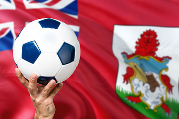 Bermuda soccer concept. National team player hand holding soccer ball with country flag background....