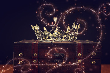 low key image of beautiful queen/king crown over wooden table. vintage filtered. fantasy medieval period. Glitter sparkle lights