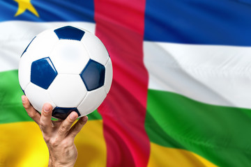 Naklejka premium African Republic soccer concept. National team player hand holding soccer ball with country flag background. Copy space for text.
