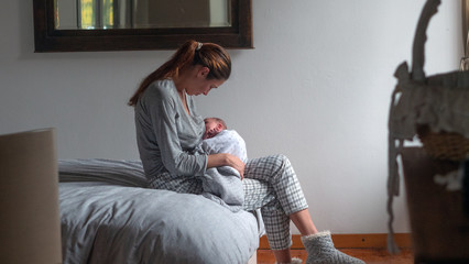 Authentic shot of neo mother is breastfeeding and caressing her newborn baby in a nursery in a...