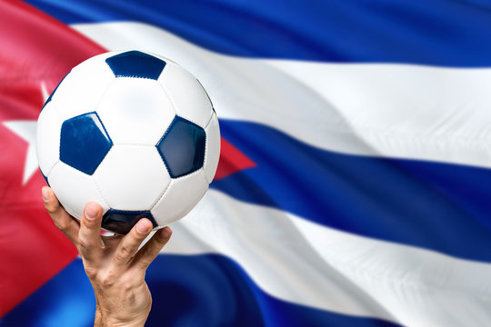 Cuba soccer concept. National team player hand holding soccer ball with country flag background. Copy space for text. - Powered by Adobe