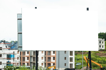 Blank white advertising billboard in the front of construction site on residential area