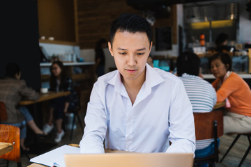 Ethnic freelancer using laptop at table in cafeteria