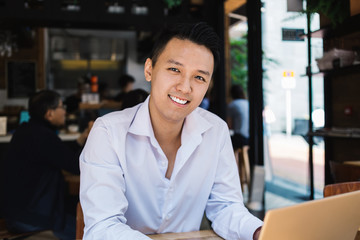 Happy freelancer working on laptop in cafe