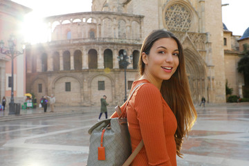 Portrait of beautiful tourist woman in Valencia with Cathedral on the background. Smiling traveler...