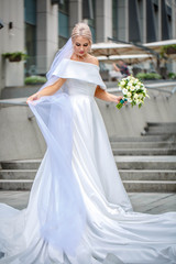 Obraz premium portrait of a beautiful bride in long dress and viel on the background of a business center
