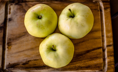 Naklejka na ściany i meble Three green organic healthy apples on wooden board.