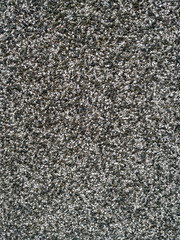 Rough texture of an old black and white grey traditional wall with visible pattern of small grains of small rocks and other materials on an old and aged building