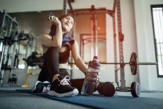 Young woman drinking water and taking a break after workout in gym,fitness concept.
