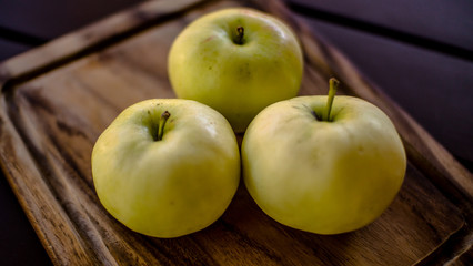 Naklejka na ściany i meble Three green organic healthy apples on wooden board.