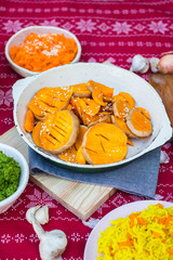 Grilled baked pumpkin slices in pan on red Christmas tablecloth background.