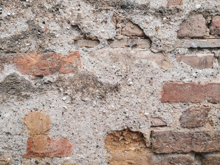 Rock stone old looking and worn wall background made of bricks on a wall of the building in the outdoors facade with rough texture and interesting natural material pattern
