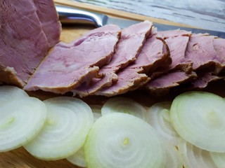  close-up of smoked meat on a wooden plate with onions