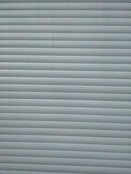 Grey metallic garage door gate for parking car and for safety, made of stainless steel but with signs of age and dirt