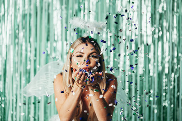 Brazilian Carnival. Young woman in costume enjoying the carnival party blowing confetti