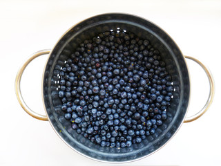 Bowl of fresh blueberries on rustic wooden old table. Freshly picked blueberries in bowl. Healthy organic fruit background. Organic food raw blueberries and mint leaf for healthy lifestyle.