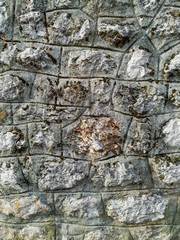 Rock stone wall background made of bricks on a wall of the building in the outdoors with rough texture and interesting natural pattern old looking cement
