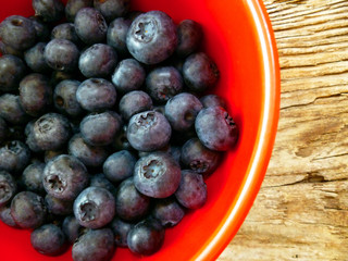 Bowl of fresh blueberries on rustic wooden old table. Freshly picked blueberries in bowl. Healthy organic fruit background. Organic food raw blueberries and mint leaf for healthy lifestyle.