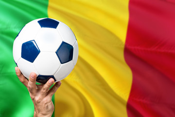 Naklejka premium Mali soccer concept. National team player hand holding soccer ball with country flag background. Copy space for text.