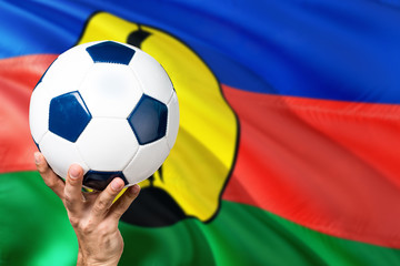 New Caledonia soccer concept. National team player hand holding soccer ball with country flag...