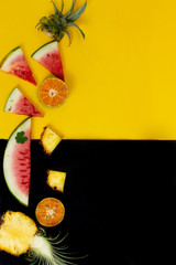 Fototapeta na wymiar exotic tropical fruits, pineapple, orange, watermelon isolated on a black yellow background