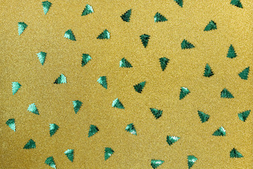Rows of green Christmas trees in rows lie on a gold background. Top view, flat lay, copy space.