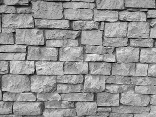 Modern retro style round rock stone uneven wall background on a wall of the building in the outdoors with rough texture and pattern in black and white