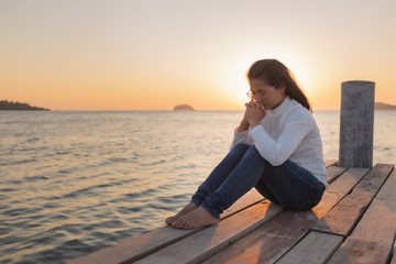 The girl sits in prayer to God with a promise. With love for God At sea ocean Outdoors during the...