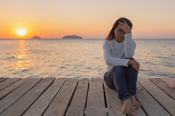 beautiful Lonely woman sitting on a wooden bridge sunset.are Lonely.Single women sat with stress