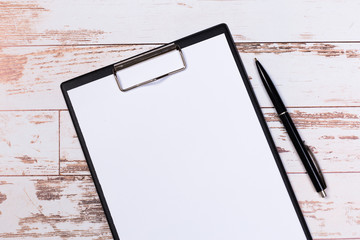 pen on blank white document sheet on wood clipboard on white wood table top view space