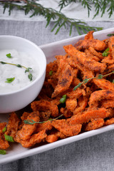 Spicy sweet potato fried sticks and yogurt sauce served on white ceramic plate