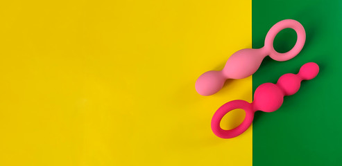 Banner. Butt plugs. Three sex toys. Yellow and green  background. Useful for sex shop. 