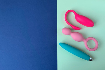 Two vibrators and anal plug. Sex toys.  Two colors background (blue and green). Useful for sex shop. 