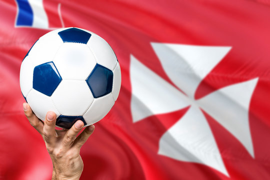 Wallis And Futuna soccer concept. National team player hand holding soccer ball with country flag background. Copy space for text. - Powered by Adobe