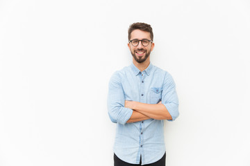 Joyful positive guy posing with arms folded. Handsome young man in casual shirt and glasses...