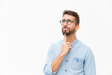 Positive pensive male customer studying special offer, looking up at copy space. Handsome young man...