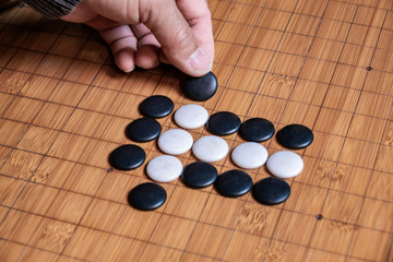 Plakat Go board game playing. A competitor is placing a marble piece on a Go board game
