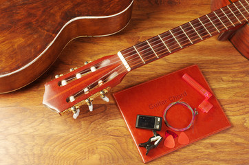 Naklejka premium Acoustic guitar and guitar accessories on a wooden textured background