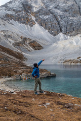 Obraz premium Happy tourist at top of mountain at outdoors during a hike the summit of mountain peak. Success freedom and happiness achievement in mountains. Active sport concept