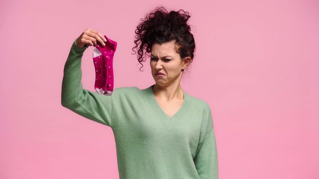 curly woman holding smelly socks isolated on blue
