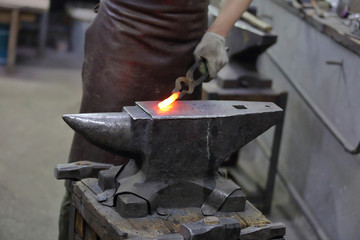 Forging an iron handmade product in a craft forge workshop