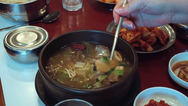 Hand stirring spoon Korean soup with mushrooms and meat