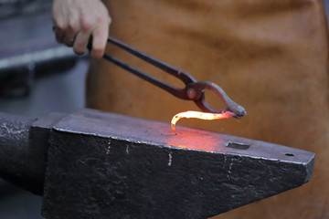 Forging an iron handmade product in a craft forge workshop