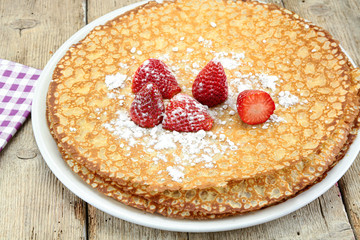 Breton crêpes and strawberries on a wooden table